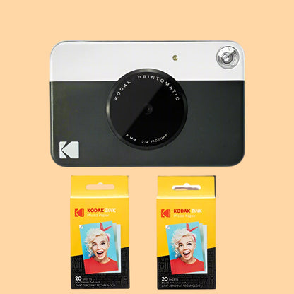 Kodak Printomatic camera with two packages of Kodak photo paper on a white background