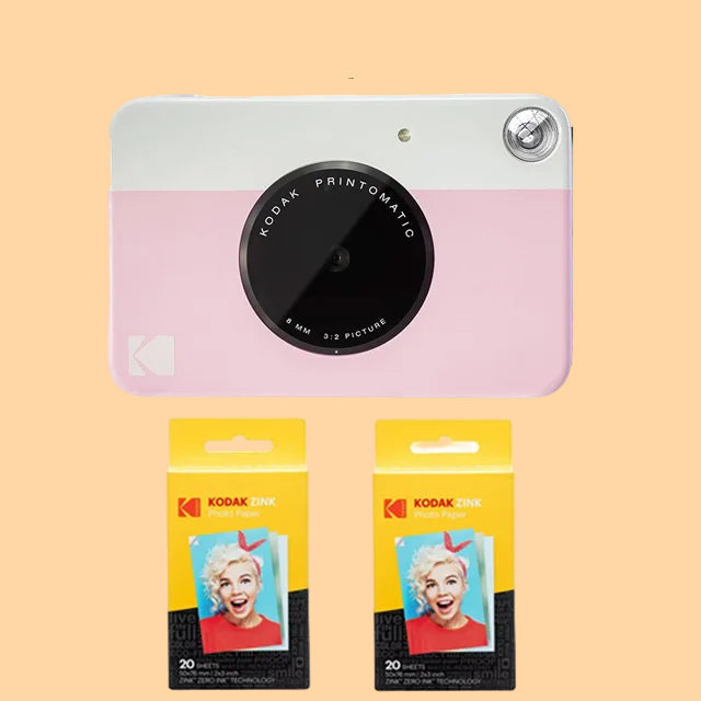 Pink Kodak Printomatic camera with two packages of Kodak photo paper on a white background
