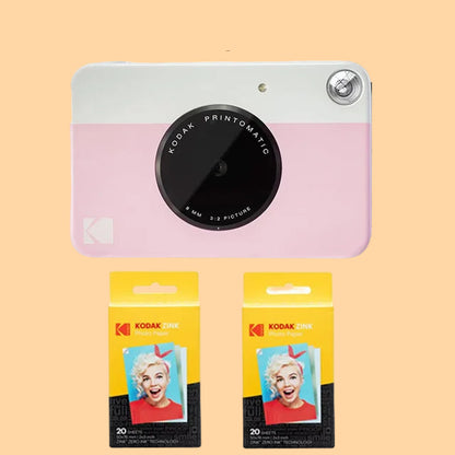 Pink Kodak Printomatic camera with two packages of Kodak photo paper on a white background