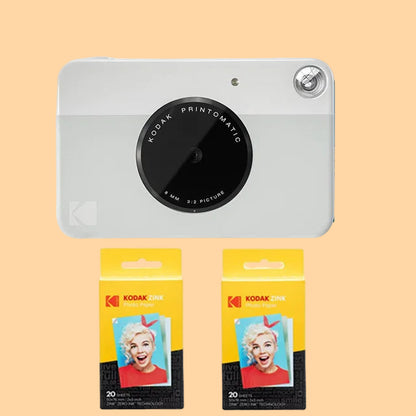 Kodak Printomatic camera with two packages of Kodak photo paper on a white background